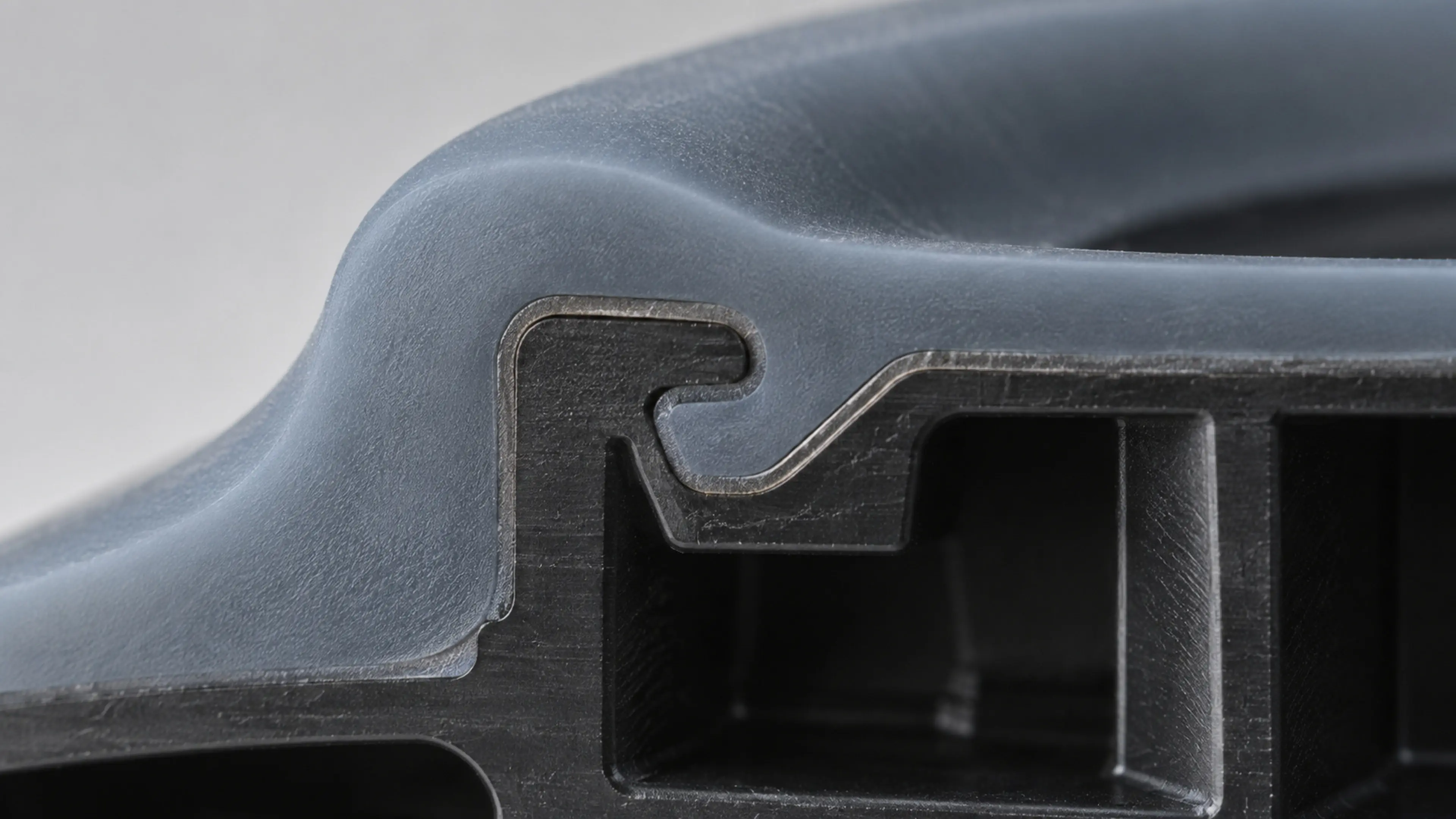 Row of overmolded silicone-on-plastic test coupons, one clamped in a peel fixture.